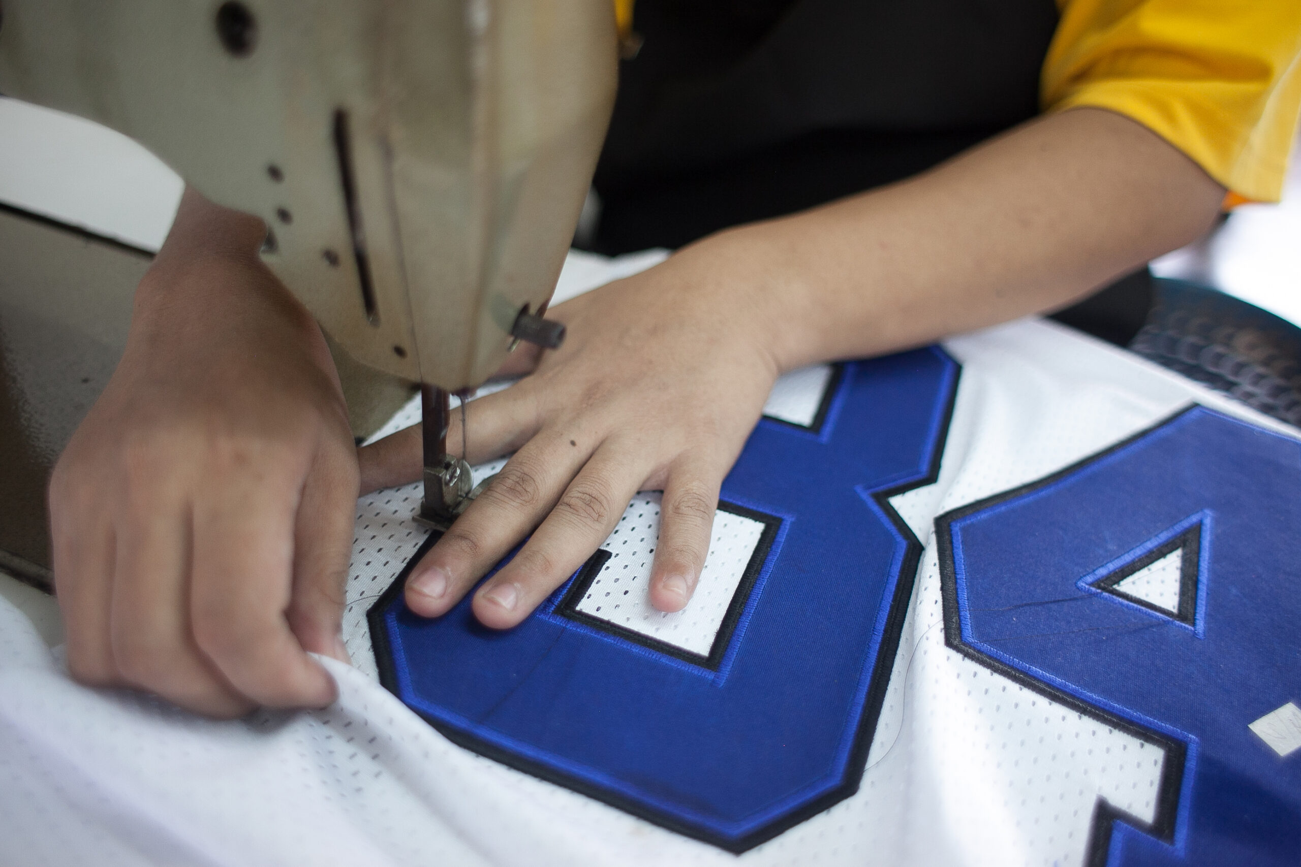 Allen Sportswear craftsperson at the sewing machine stitching custom team uniforms